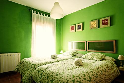 a green bedroom with two beds and a window at Casa La Alegria De La Alcarria II in Sigüenza