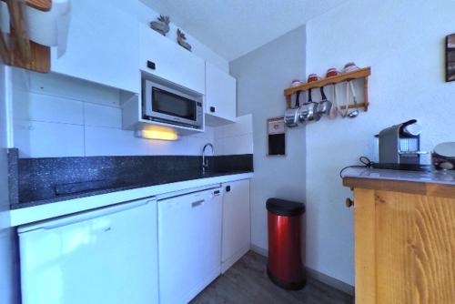 レ・デュー・アルプにあるLe Diamantの白いキャビネットと赤いゴミ箱付きのキッチン