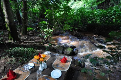 a picnic table with flowers on it next to a stream at La Mada Hotel in Nairobi