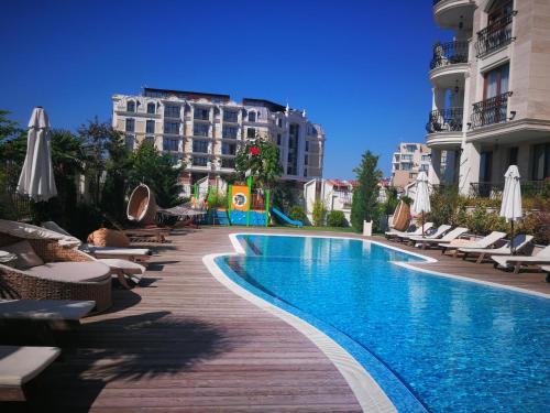 a swimming pool with chairs and umbrellas next to buildings at Harmony Suites Apartment in Sveti Vlas