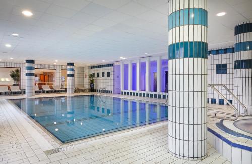 a large swimming pool in a large building at Hôtel Spa Du Béryl in Bagnoles de l'Orne