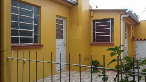una casa amarilla con una puerta blanca y una valla en Apartamento kitchenette en São Lourenço do Sul