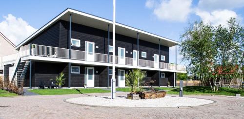 a black building with a balcony on the side of it at De Berkenhof in Nes