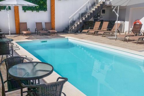 einen Pool mit Stühlen, einem Tisch und einer Treppe in der Unterkunft Hotel Rosa Mística by Umbral in Fátima