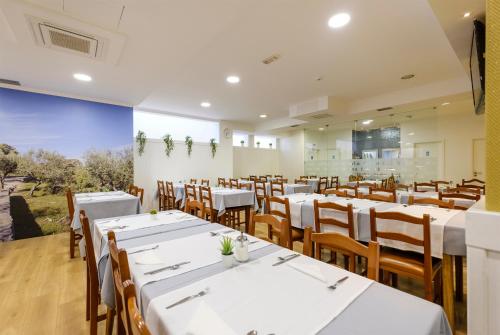 a dining room with white tables and wooden chairs at Hotel Rosa Mística by Umbral in Fátima