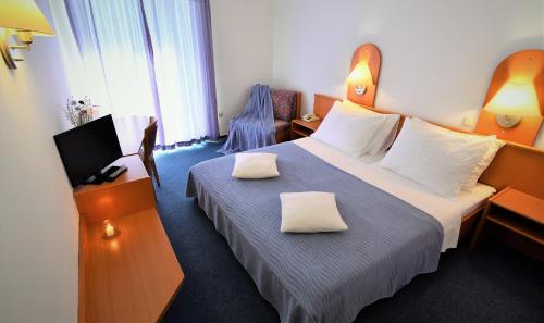 a hotel room with a bed with two pillows on it at Hotel Alkar in Sinj