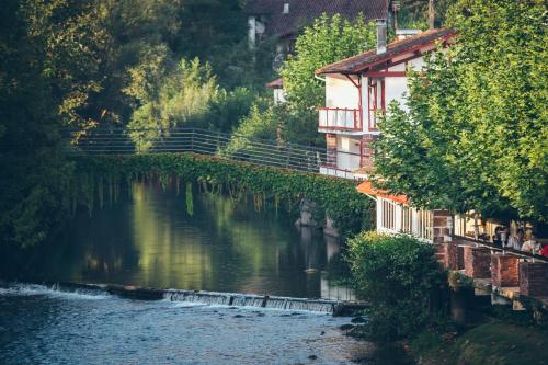 a river with buildings next to a river with trees at Hôtel Arcé in Saint-Étienne-de-Baïgorry