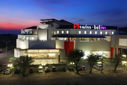 a building with cars parked in a parking lot at night at Swiss-Belinn Panakkukang in Makassar