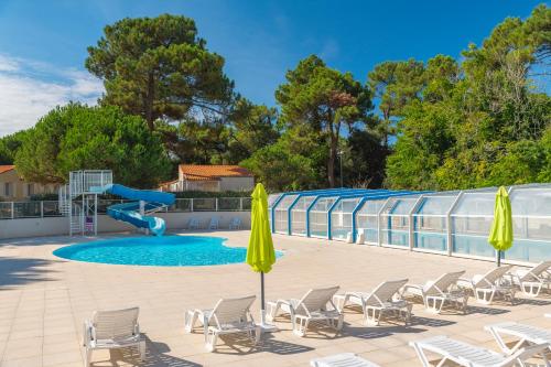 uma piscina com cadeiras e um escorrega em Azureva Ile d'Oleron em Grand-Village-Plage