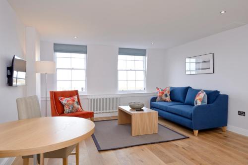 a living room with a blue couch and a table at Destiny Scotland New Town Apartments in Edinburgh