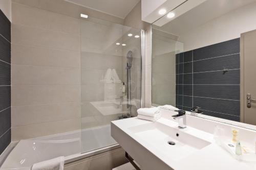 La salle de bains est pourvue d'un lavabo, d'une baignoire et d'un miroir. dans l'établissement Best Western Crequi Lyon Part Dieu, à Lyon