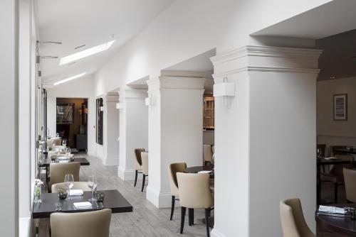 a restaurant with white columns and tables and chairs at Dunalastair Hotel Suites in Kinloch Rannoch
