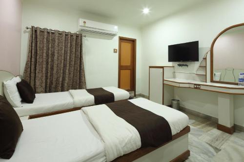 a hotel room with two beds and a mirror at Hotel Good Night in Ahmedabad