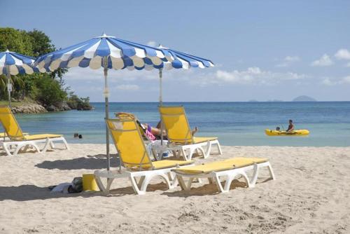 a group of chairs and an umbrella on a beach at Studio Yucca, Pointe de la verdure, Didier BERVILLE in Le Gosier