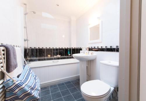 een badkamer met een toilet, een wastafel en een bad bij Stunning home with breathtaking sea views in Penzance