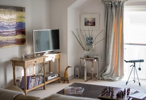 a living room with a tv on a wooden table at Stunning home with breathtaking sea views in Penzance