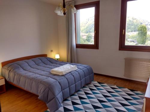 a bedroom with a blue bed and two windows at Bright Apartment in Marostica in Marostica