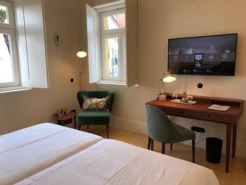 a bedroom with a bed and a desk and a tv at Montebelo Vista Alegre Ílhavo Hotel in Ílhavo