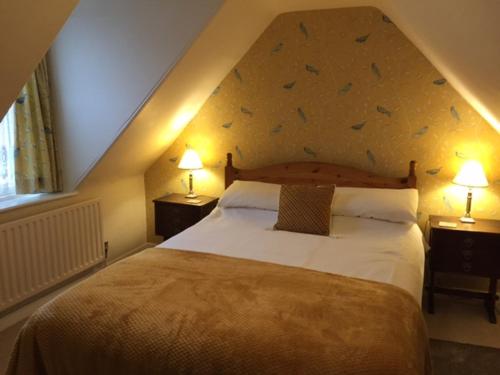 a bedroom with a large bed and two lamps at Lazydays Cottage in Moffat