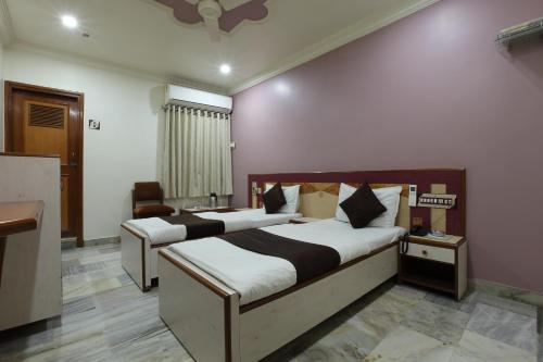 two beds in a room with pink walls at Hotel Good Night in Ahmedabad