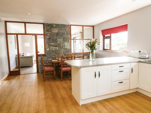 cocina con armarios blancos y comedor con mesa en High View en Killarney