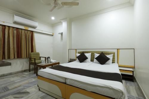 a hotel room with a bed and a chair at Hotel Good Night in Ahmedabad