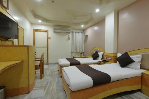 a hotel room with two beds and a television at Hotel Good Night in Ahmedabad