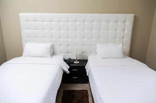 2 camas con sábanas blancas y cabecero en una habitación en Hotel Royal Residencial en Maputo