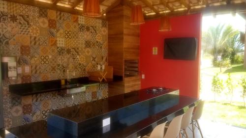 cocina con encimera negra y pared roja en Quinta das Lagoas Residence, en Itacimirim
