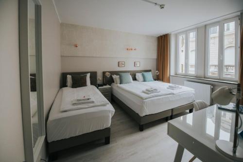 um quarto de hotel com duas camas e uma janela em Le Chatelet em Luxemburgo