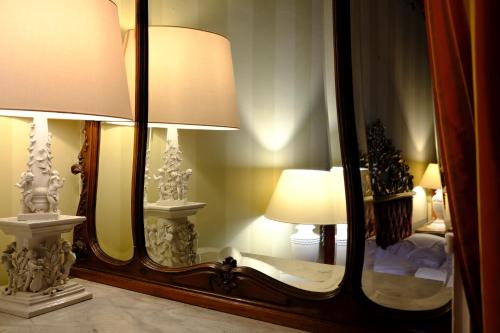 a mirror with a lamp and a bed in a room at Al Tuscany in Lucca