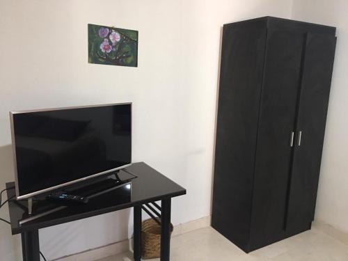 Apartaestudio en Chia في شيا: خزانة سوداء بجوار طاولة مع تلفزيون
