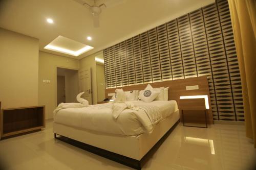 a bedroom with a large white bed and a television at Noor jehan's Grand Noor in Palakkad