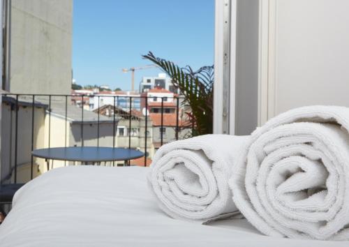 a pile of white towels on a bed on a balcony at Downtown Colosseum Apartments in Porto