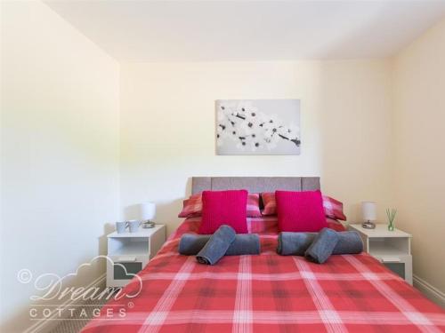 a bedroom with a large red bed with red pillows at Markham Cottage in Weymouth