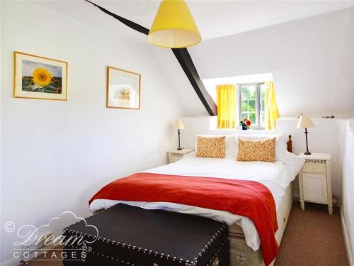 1 dormitorio con 1 cama grande con manta roja en Little Berwick Cottage en Burton Bradstock