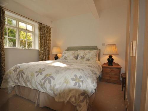 a bedroom with a bed and two lamps and a window at Fountain Cottage in Weymouth