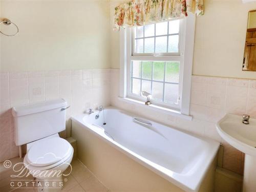 uma casa de banho com uma banheira, um WC e uma janela. em Pippins em Dorchester
