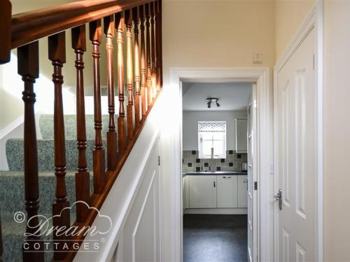einen Flur mit einer Treppe, die zu einer Küche führt in der Unterkunft Rupert Cottage in Weymouth