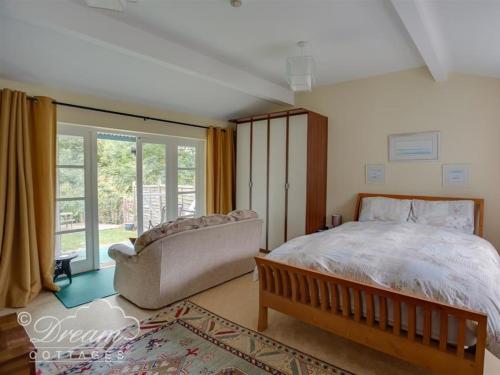 ein Schlafzimmer mit einem Bett und einer Couch und einem Fenster in der Unterkunft Harbour View Bungalow in Weymouth
