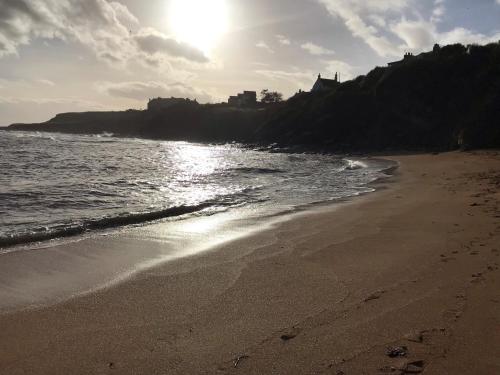 a beach with the sun shining on the water at Sandpipers in Anstruther