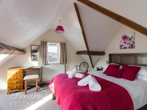 a bedroom with a large bed with a red blanket at Buccaneer Cottage in Weymouth