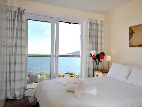 a bedroom with a large white bed and a large window at Rainbow's End in Weymouth