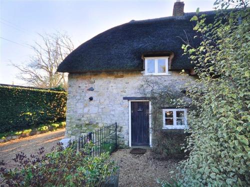 a small stone house with a thatched roof at Little Ivy in West Lulworth