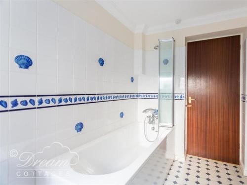 a bathroom with a tub and a wooden door at Buccaneer Cottage in Weymouth