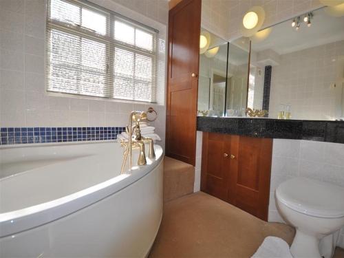 a bathroom with a tub and a toilet and a sink at Fountain Cottage in Weymouth