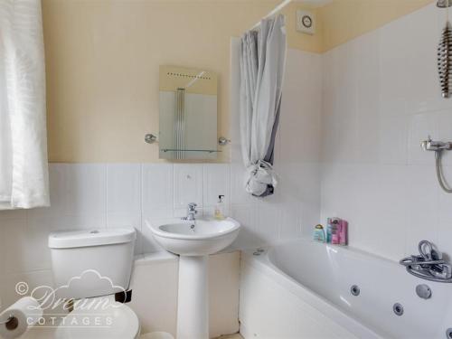 ein weißes Badezimmer mit Waschbecken, Toilette und Badewanne in der Unterkunft Harbour View Bungalow in Weymouth