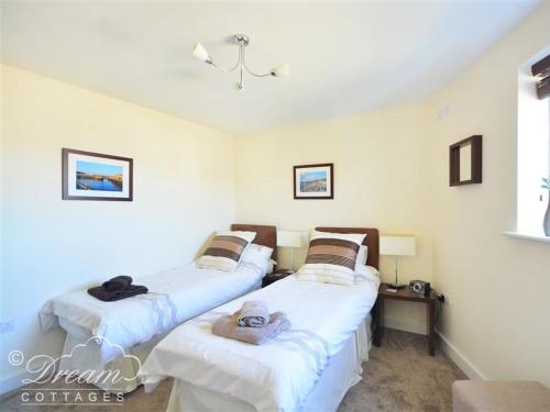 two twin beds in a room with white walls at The Boardwalk in West Bay