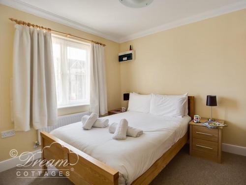 1 dormitorio con 1 cama grande con almohadas blancas en Bridge Apartment en Weymouth