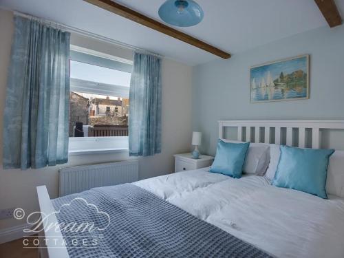 a bedroom with a bed with blue pillows and a window at Ammonite Cottage in Portland